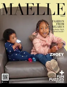 Two young Black children, one holding a toy, sit on a leather chair.