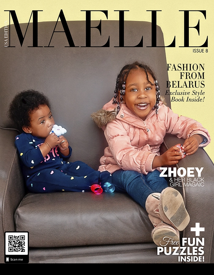 Two young Black children, one holding a toy, sit on a leather chair.