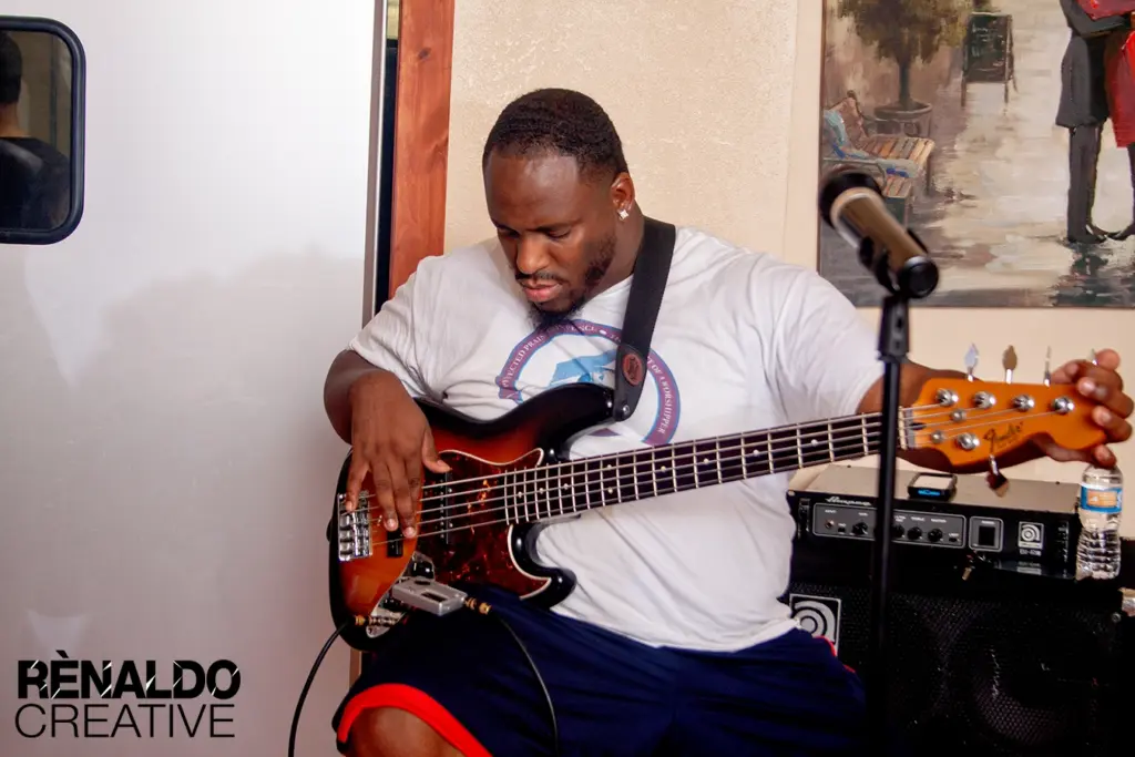 A musician plays a bass guitar during a live event, showcasing talent and engagement in a vibrant setting.