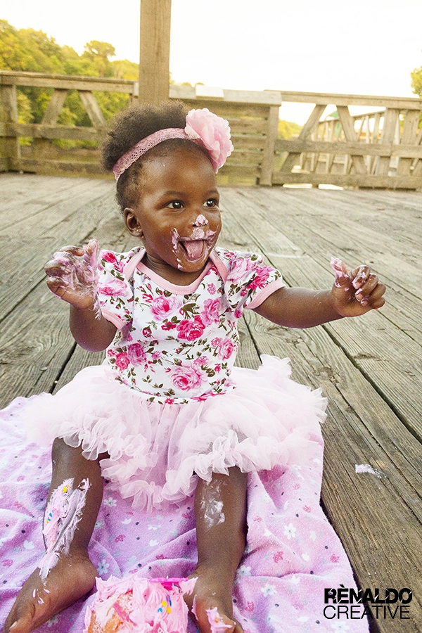 Messy toddler in pink tutu and floral romper after cake smash