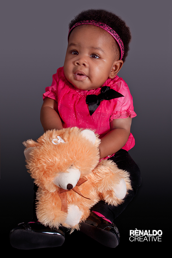 Cute baby girl in pink outfit holding a teddy bear