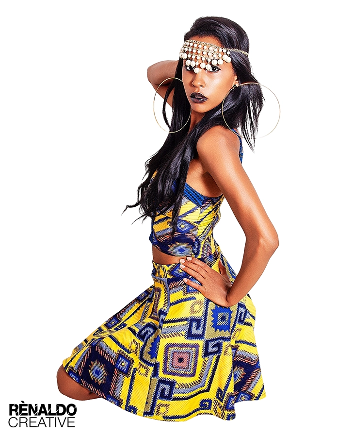 Model poses confidently in a vibrant yellow and blue patterned outfit, showcasing bold fashion and striking accessories.