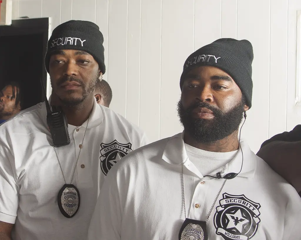 Two security guards in black beanies and white polos with badges